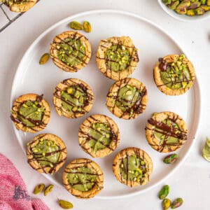 Pistachio Cream-filled Cookies cups with dark chocolate drizzle on top.