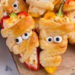 Close-up of cheese-filled mini pepper halves made to look like mummies.