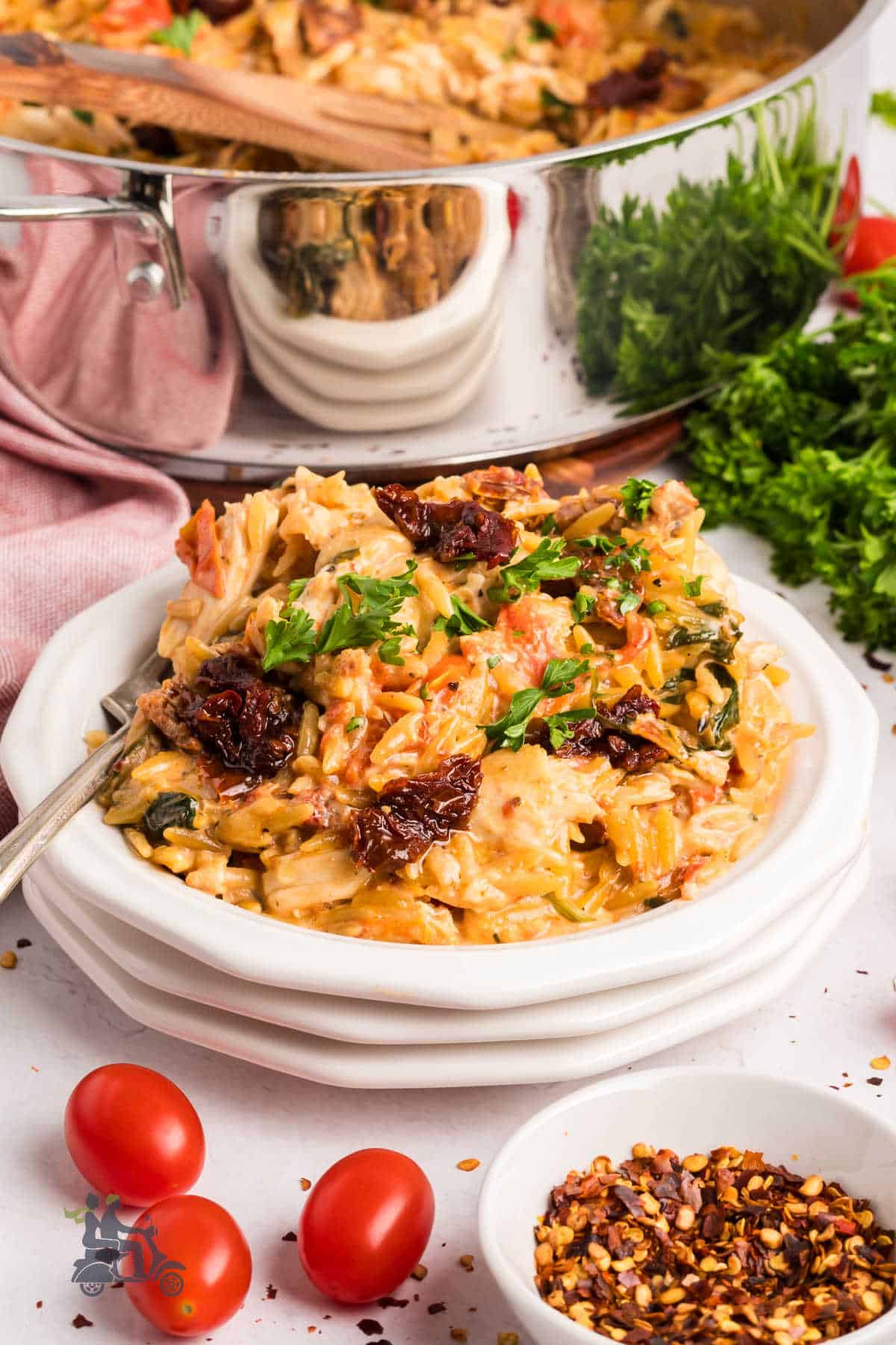 Side angle of Tuscan chicken pasta with orzo topped with fresh parsley. 