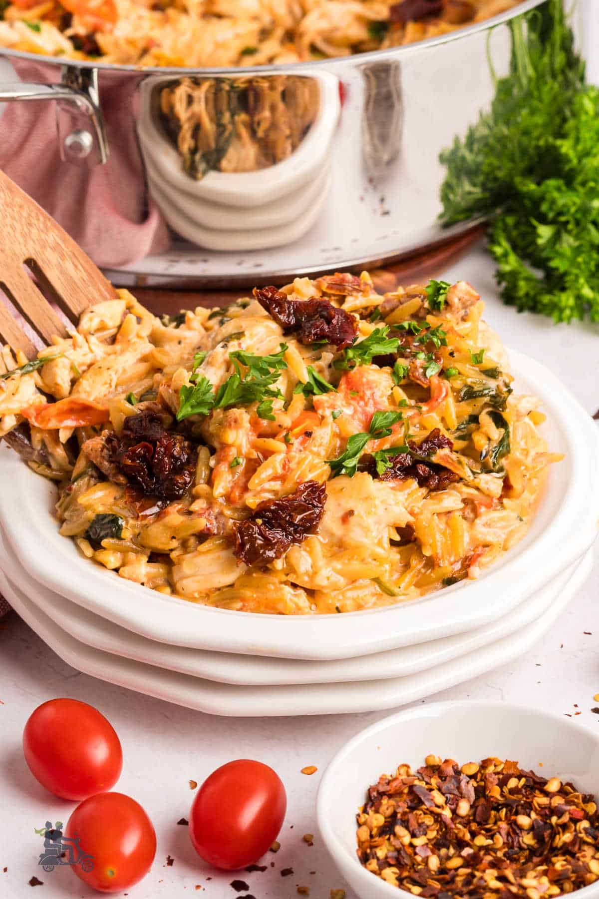 Creamy orzo pasta with chicken and Parmesan cheese served on a white plate.