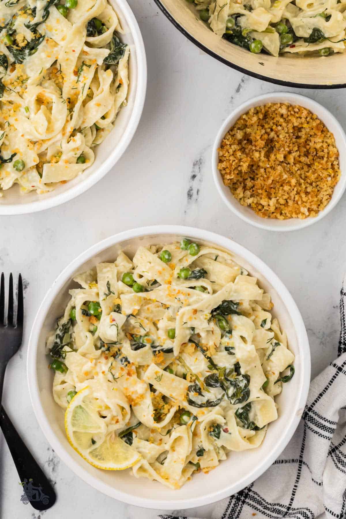 Two white bowls filled with tagliatelle pasta with spinach and creamy feta sauce.