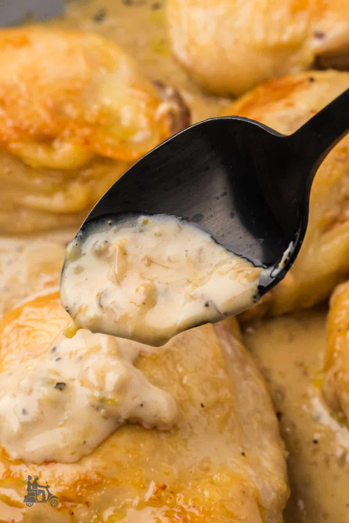A close-up of the cacio e pepe creamy sauce poured from a spoon onto a chicken thigh.