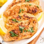 Greek Yogurt marinated chicken breasts on a white platter.