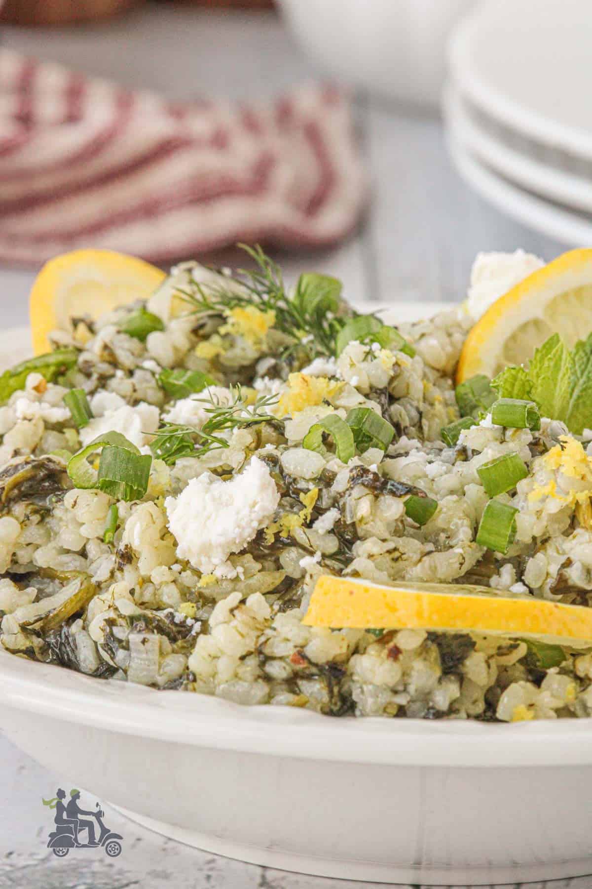 A side view of a white plate holding a serving of herby rice made in a Greek-style. 