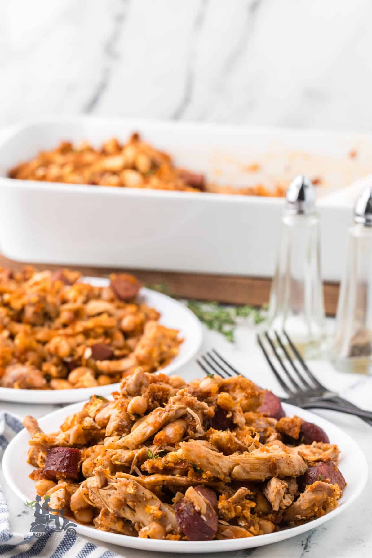 Rustic French Chicken Cassoulet recipe finished and served on white China plates with the casserole dish in the background. 
