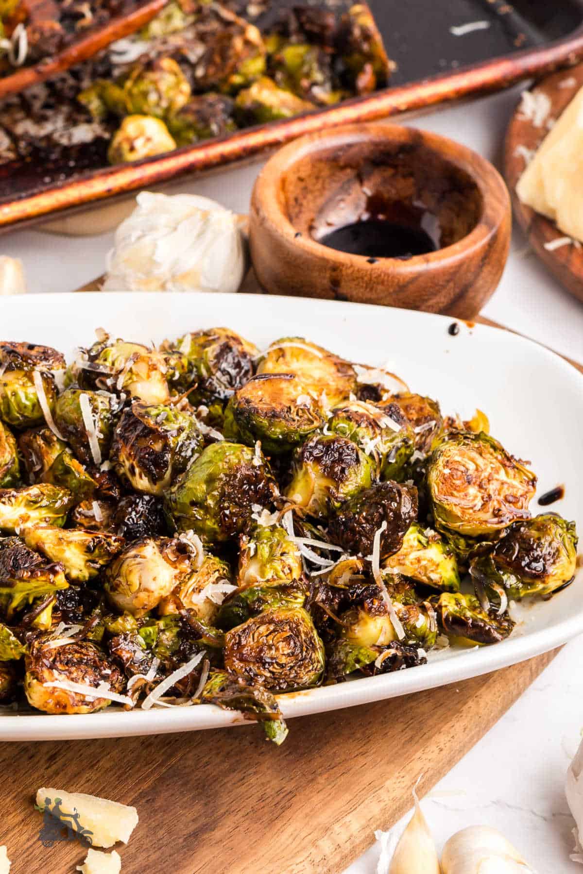 Roasted Brussels Sprouts with Parmesan and Balsamic Reduced Glaze on a white serving plate, ready to be served. 