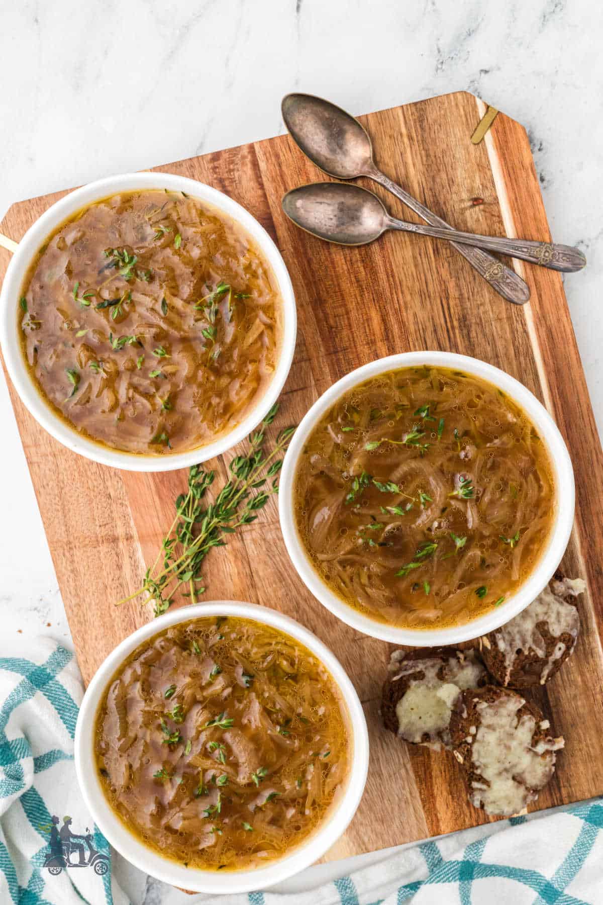 Three soup bowls filled with easy Crockpot French Onion Soup ready to have the cheese toast placed on top. 