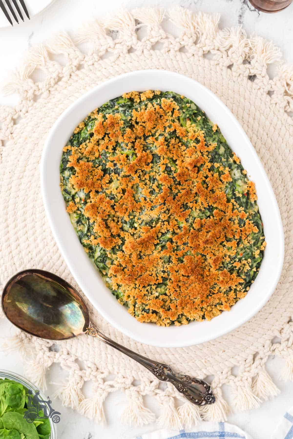 A baking dish prepared with the Southern Spicy Creamed Spinach Madeline with a breadcrumb topping.