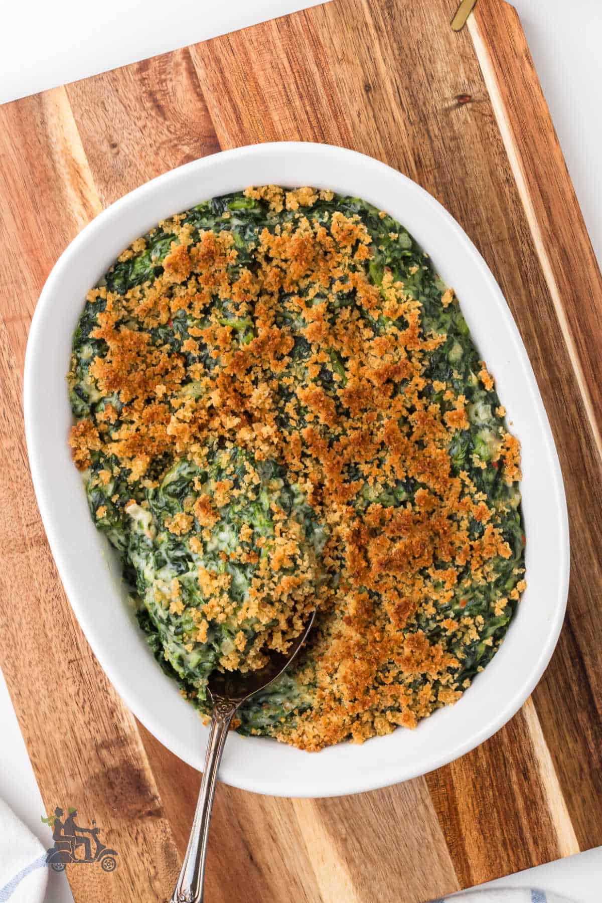 Spinach Madeline made in an oval baking dish and set on a wooden cutting board. 