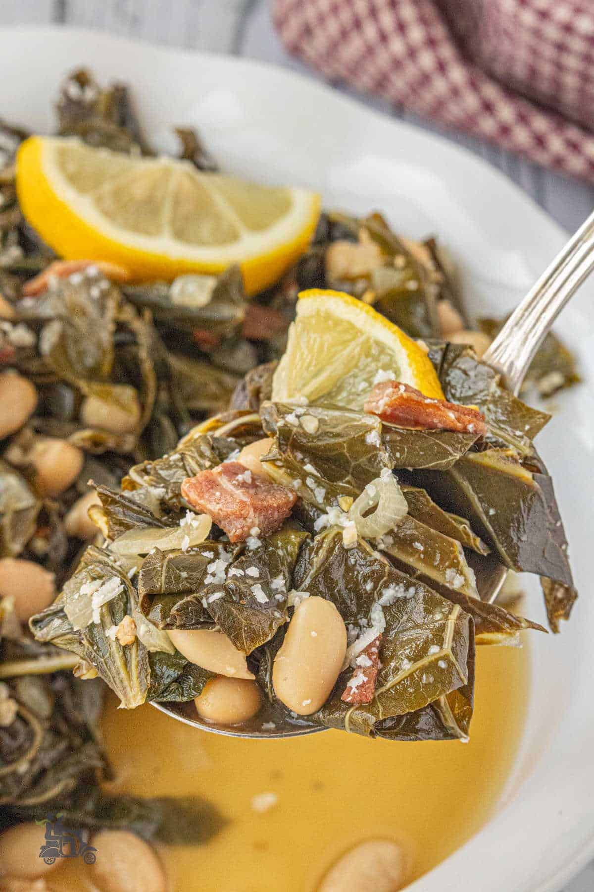 A serving spoon dishes up a heaping portion of Tuscan Collard Greens with Cannellini beans and pancetta.