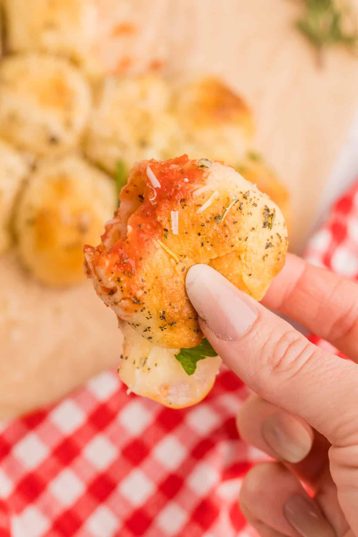 Hand holding a cheese-stuffed roll from the Christmas tree bread.