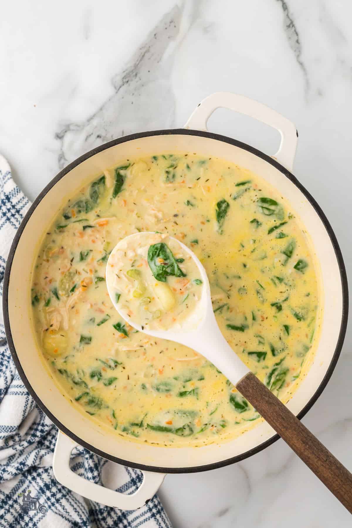 A soup ladle dipping into the pot of homemade Olive Garden copycat chicken gnocchi soup.