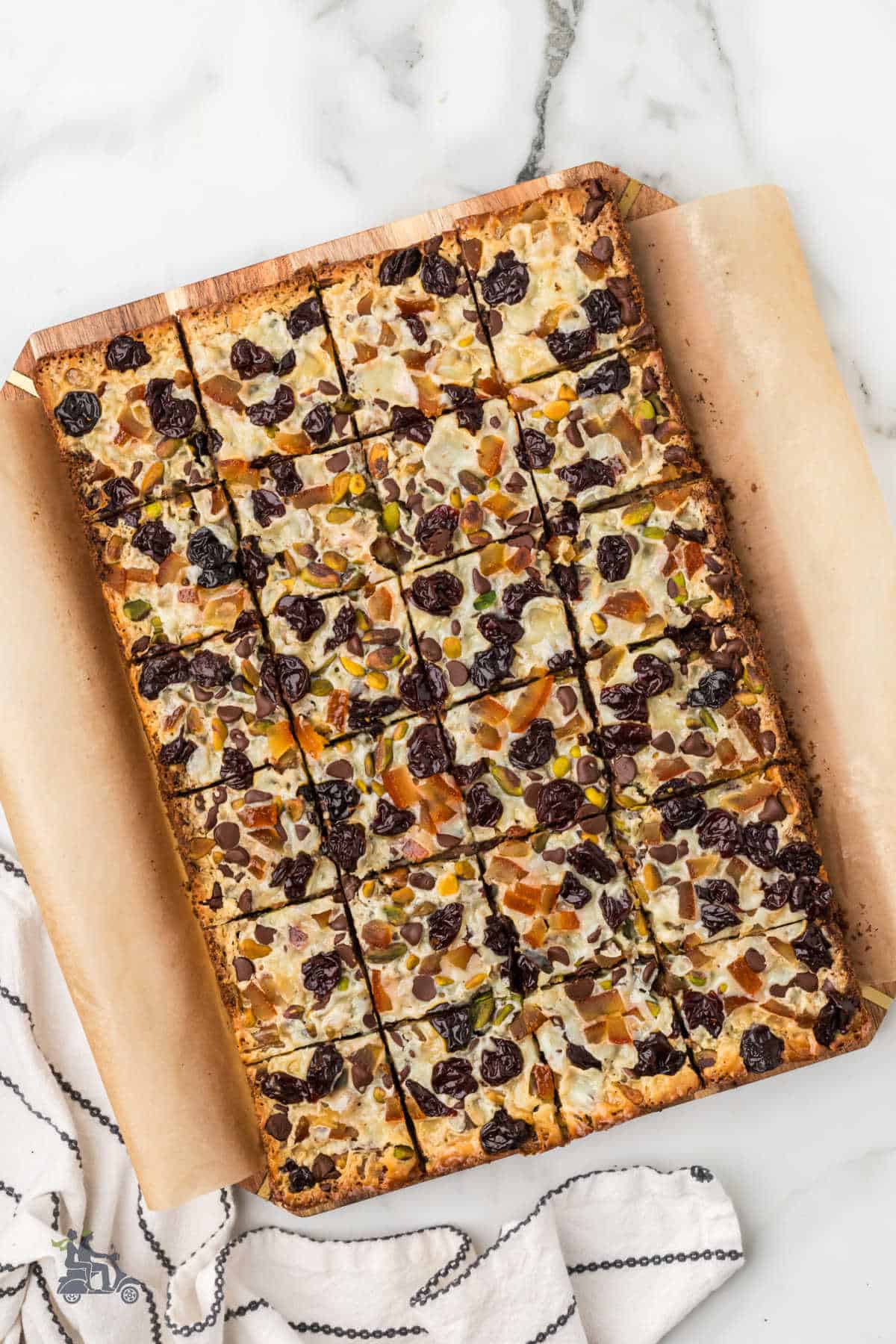 Slicing Holiday magic Bars into squares on a wooden cutting board. 