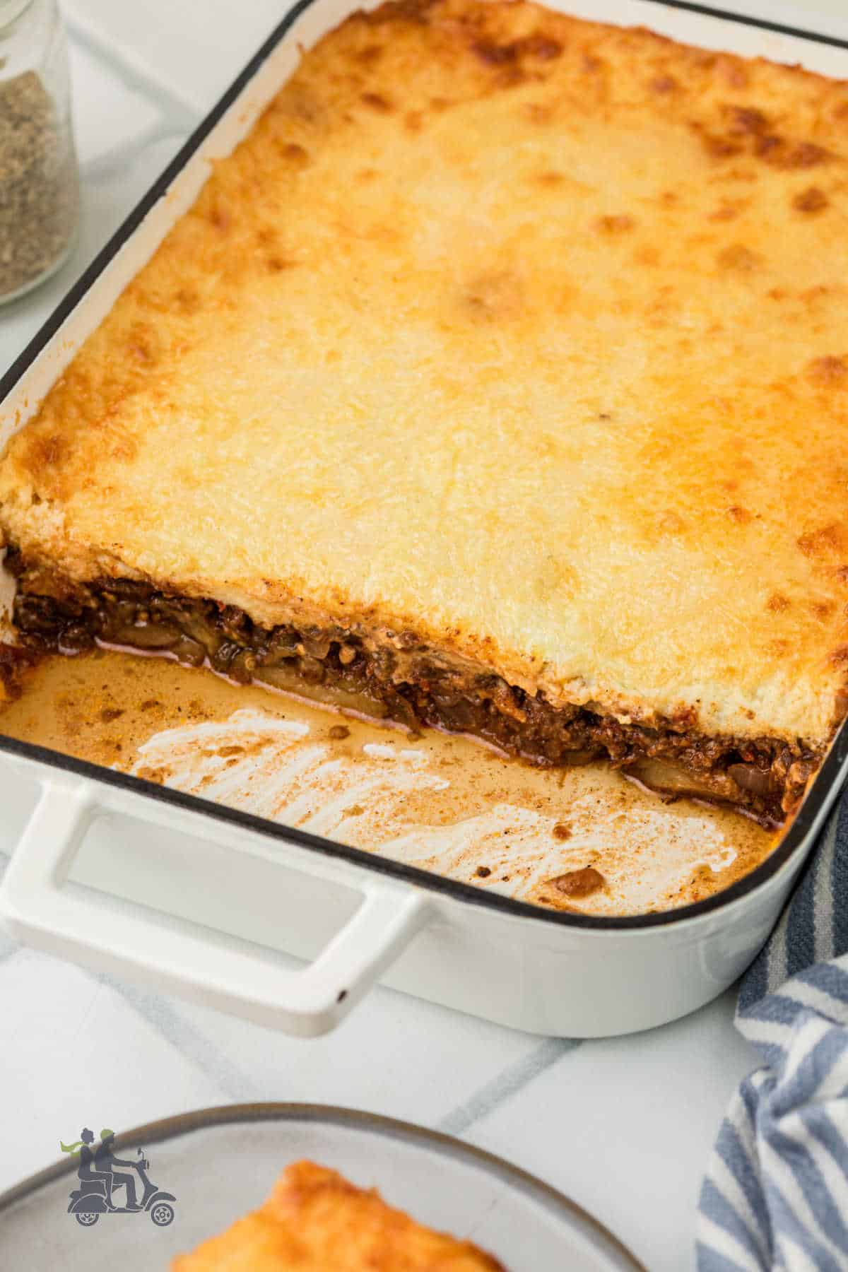 The moussaka baking dish with several helpings removed from the pan. 