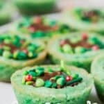 Christmas sugar cookie cups are formed into festive holiday wreaths using Reese's chocolate cups.