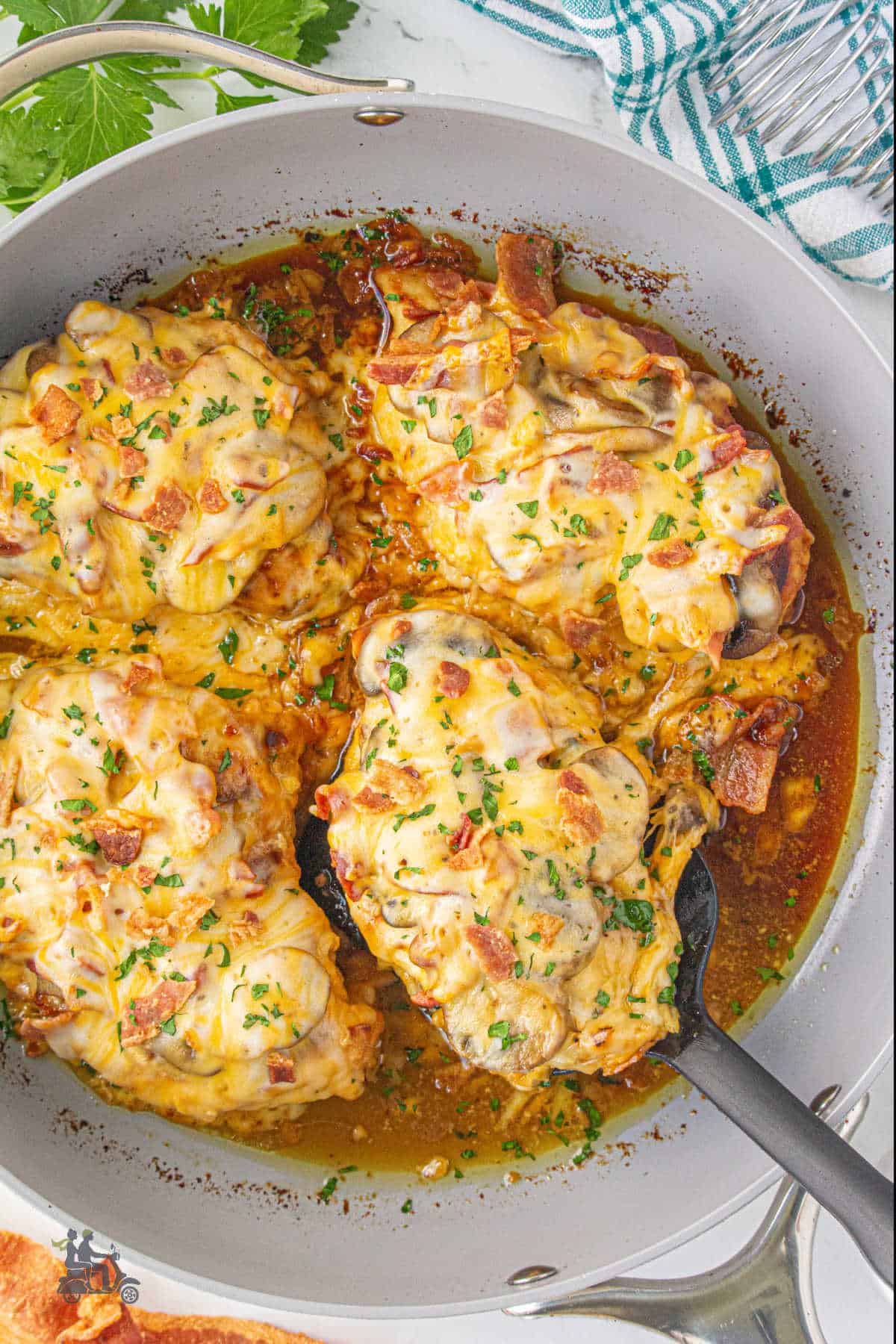 A spatula removes a chicken breast from the skillet holding the four breasts made in the Alice Springs copycat recipe. 