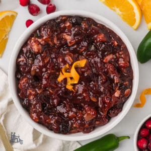 A white serving bowl holds the Cranberry Orange Relish recipe with dried cherries and jalapeño pepper.