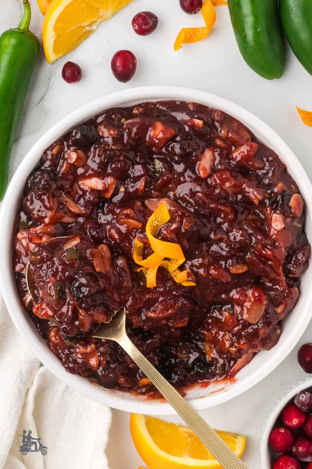 A serving spoon is in the center of the cranberry orange relish with almonds.
