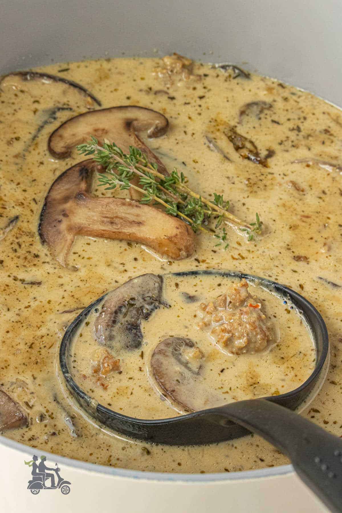 A ladle scooping up a helping of creamy mushroom soup with shiitake mushrooms.