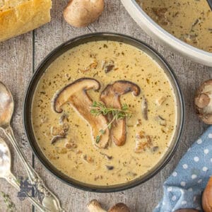 Creamy mushroom soup with Italian sausage served with a thyme sprig on top.