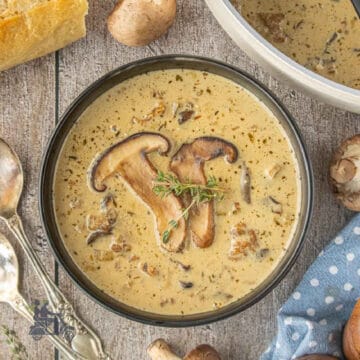 Creamy mushroom soup with Italian sausage served with a thyme sprig on top.