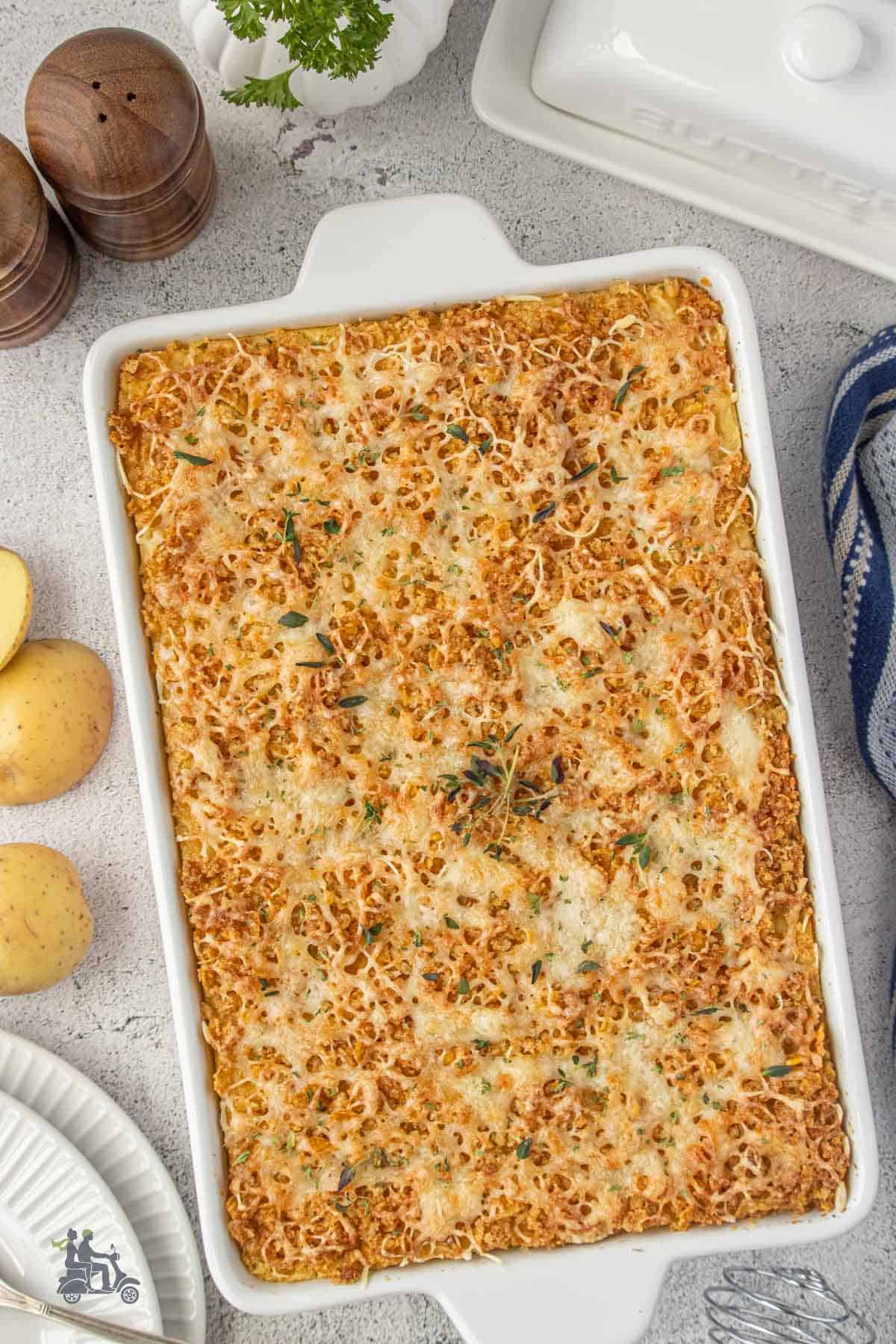 Mashed potatoes in a casserole dish with buttered panko, cornflakes, and gruyere cheese topping.