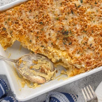 Mashed potato casserole in a baking dish with a serving spoon in the dish.