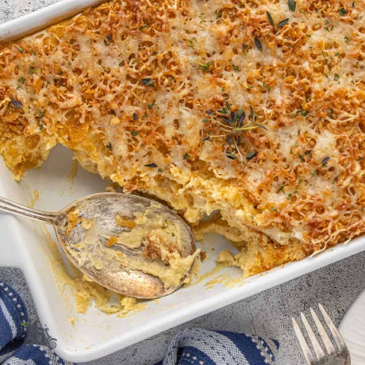Mashed potato casserole in a baking dish with a serving spoon in the dish.