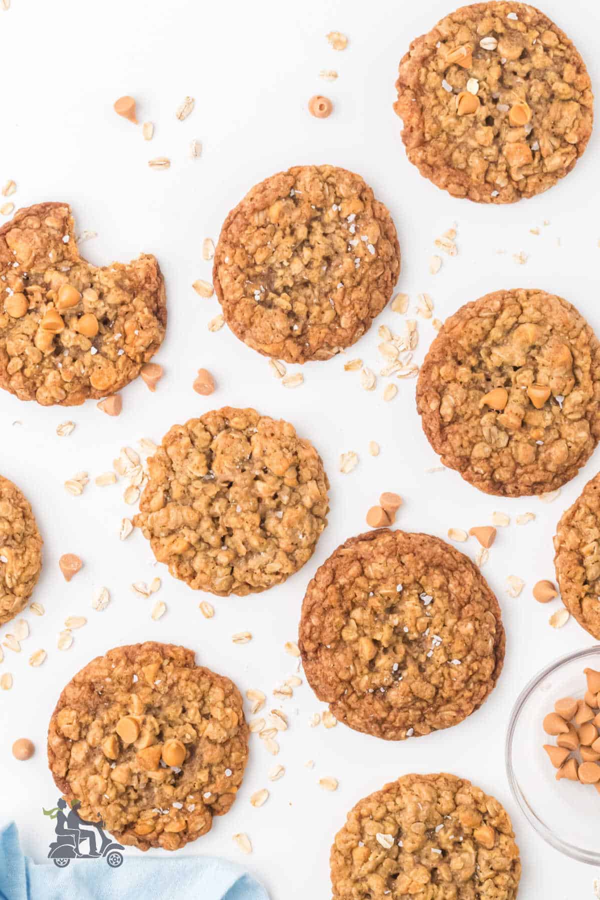 Classic oat cookies with butterscotch chips scattered on a white marble counter with additional butterscotch chips sprinkled. 