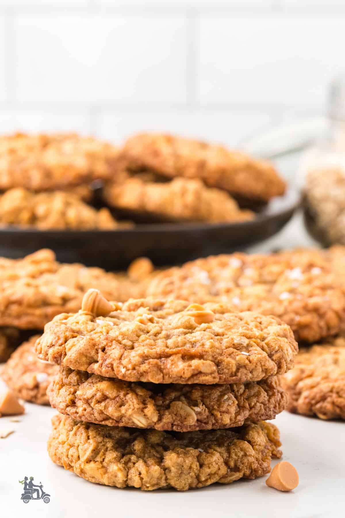 Old-fashioned oatmeal butterscotch cookies stacked on top of each other on a plate with more cookies on it. 