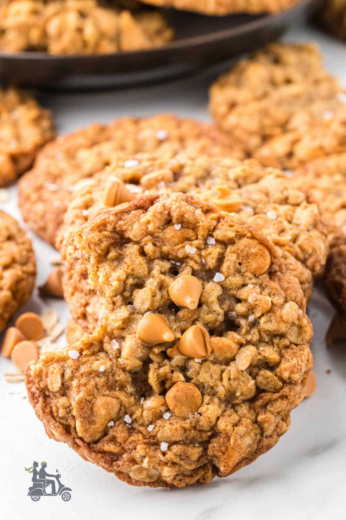 Soft and chewy oatmeal cookies with butterscotch chips piled on a country table. 