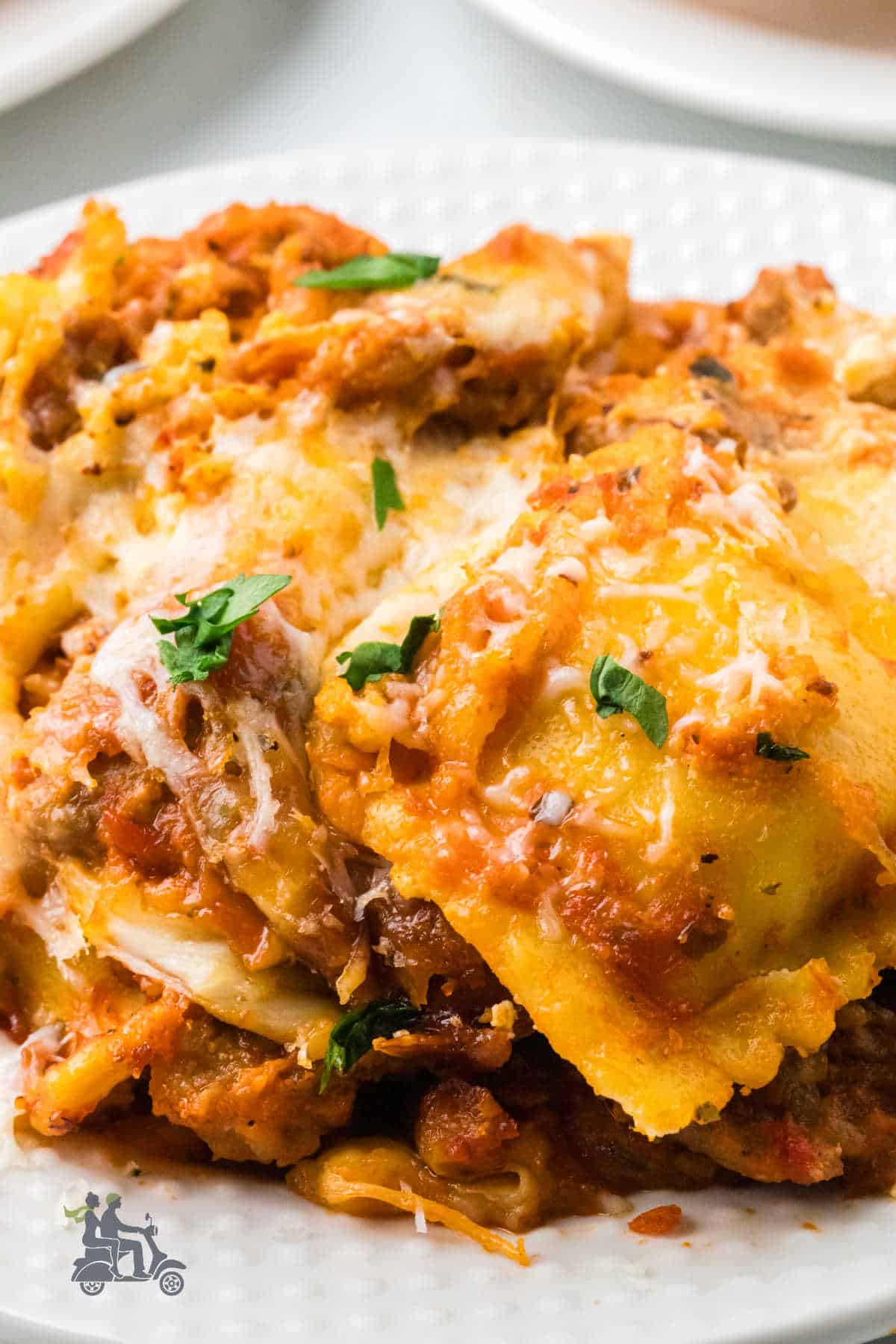 Million Dollar Ravioli Casserole with Italian sausage on a white serving plate.