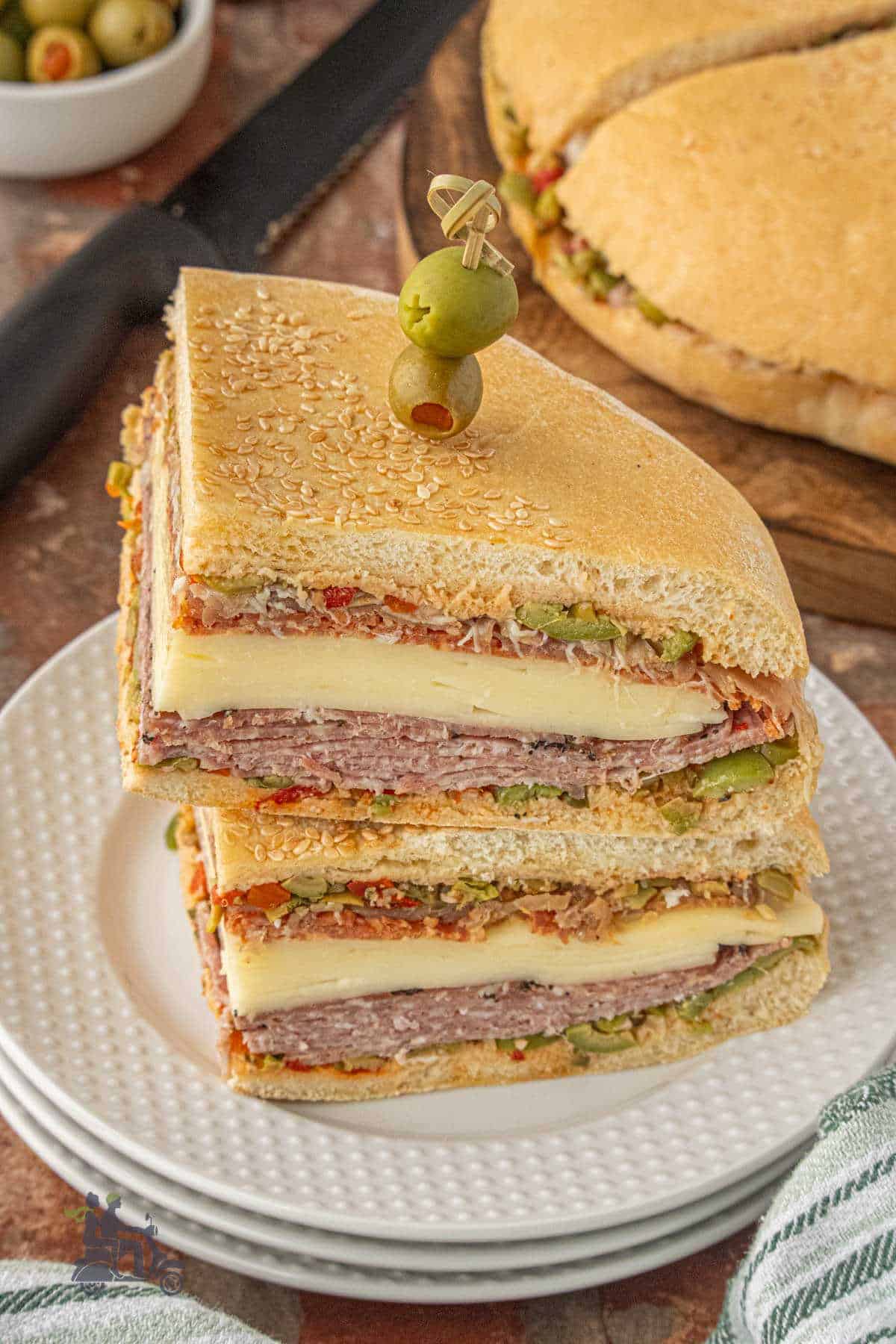 Side view of two muffuletta wedges displaying the layers of meat, cheese, and olive spread.