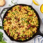Creamy ditalini pasta with peas in a black cast iron skillet, topped with fresh herbs.