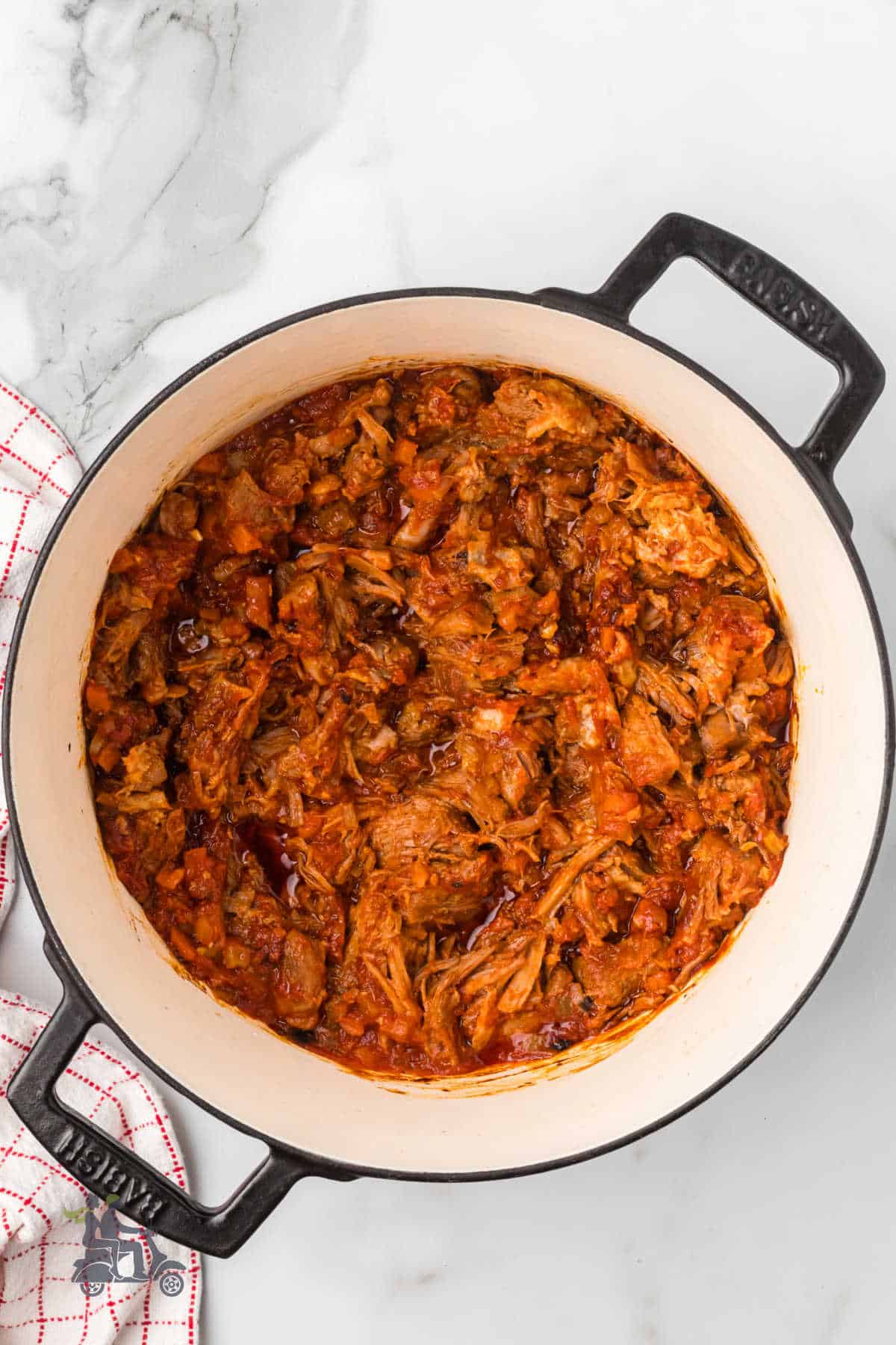 A Dutch oven holds the completed Italian pork sauce made in the Bolognese style.