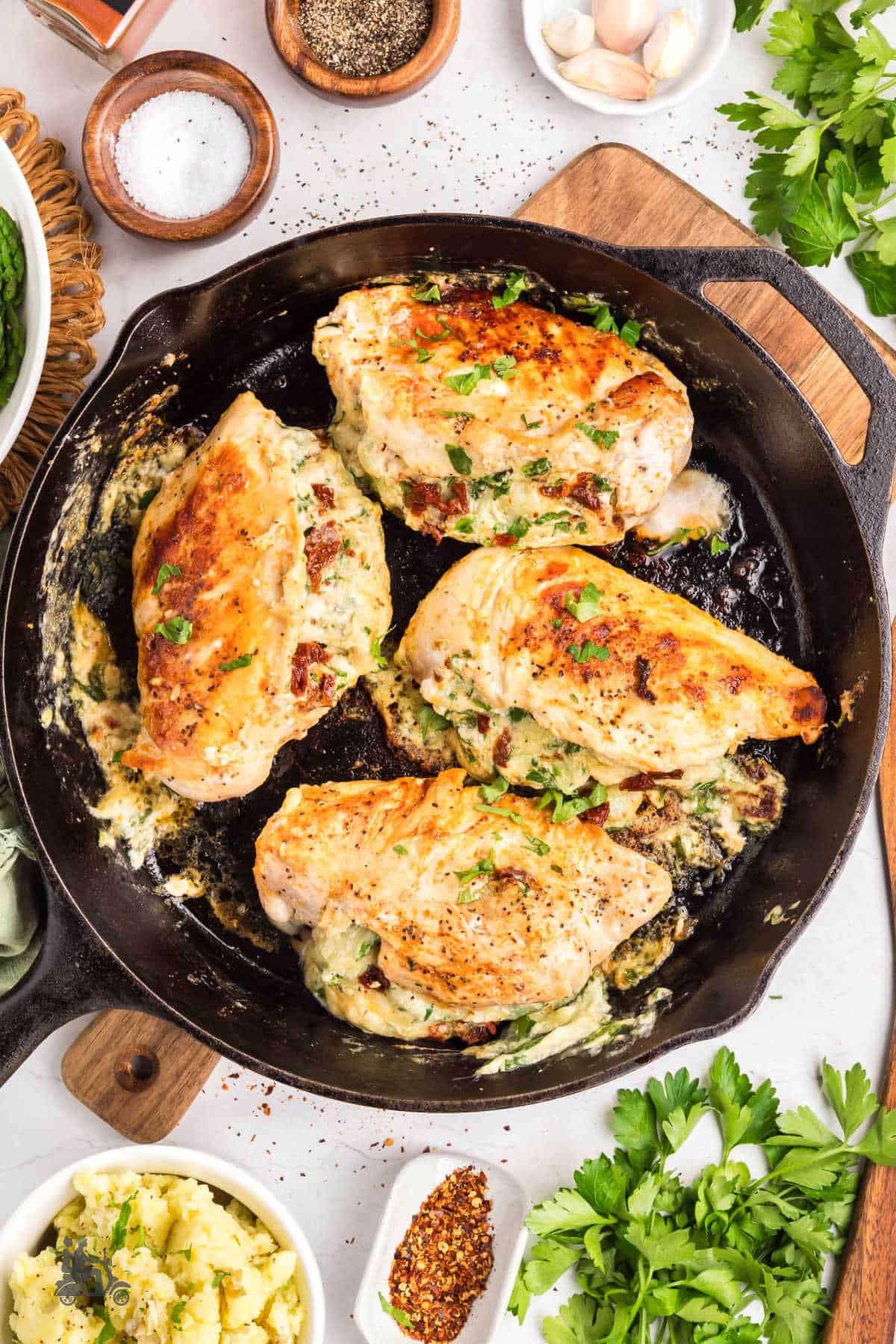 One-skillet creamy spinach stuffed chicken breasts on top of wooden cutting board. 