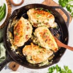 Creamy spinach and cheese stuffed chicken breasts cooked in a black skillet.