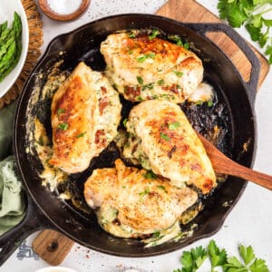 Creamy spinach and cheese stuffed chicken breasts cooked in a black skillet.