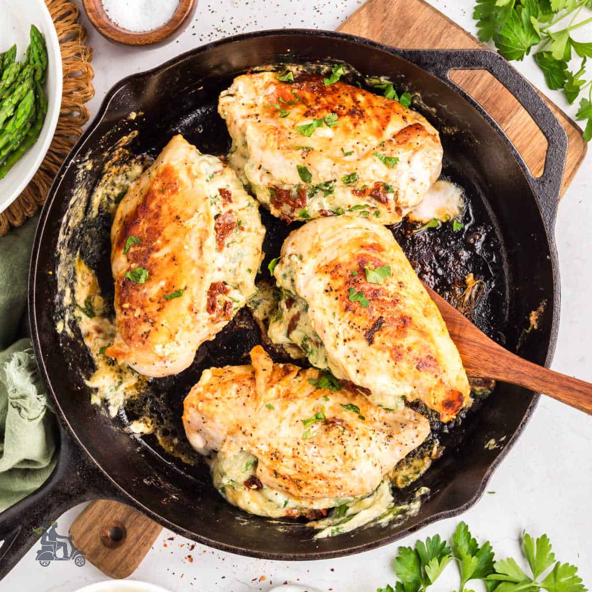 Creamy spinach and cheese stuffed chicken breasts cooked in a black skillet.