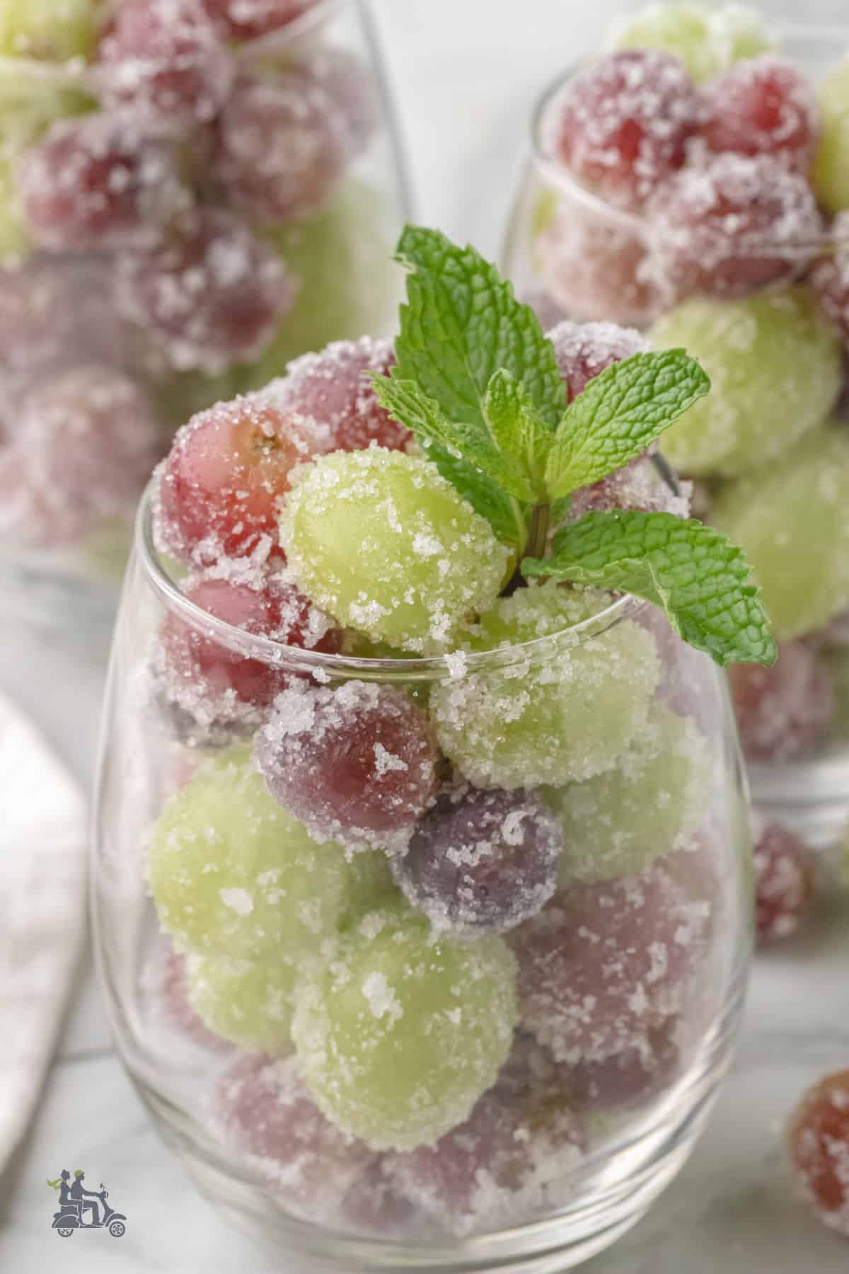Wine goblets are filled with sugared grapes that were soaked in Prosecco wine. 