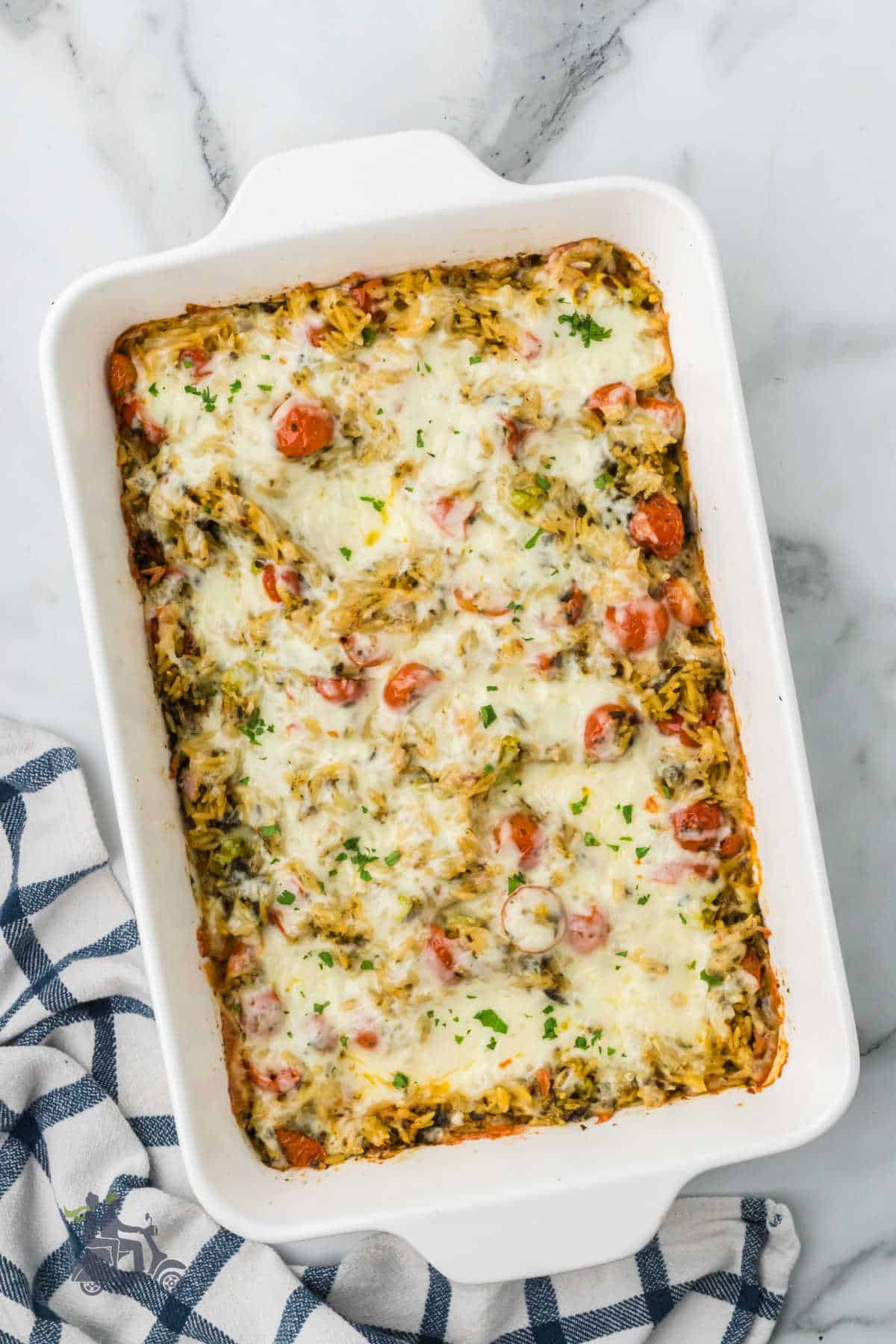 An easy family orzo pasta dinner is baked in a casserole dish and topped with mozzarella cheese.
