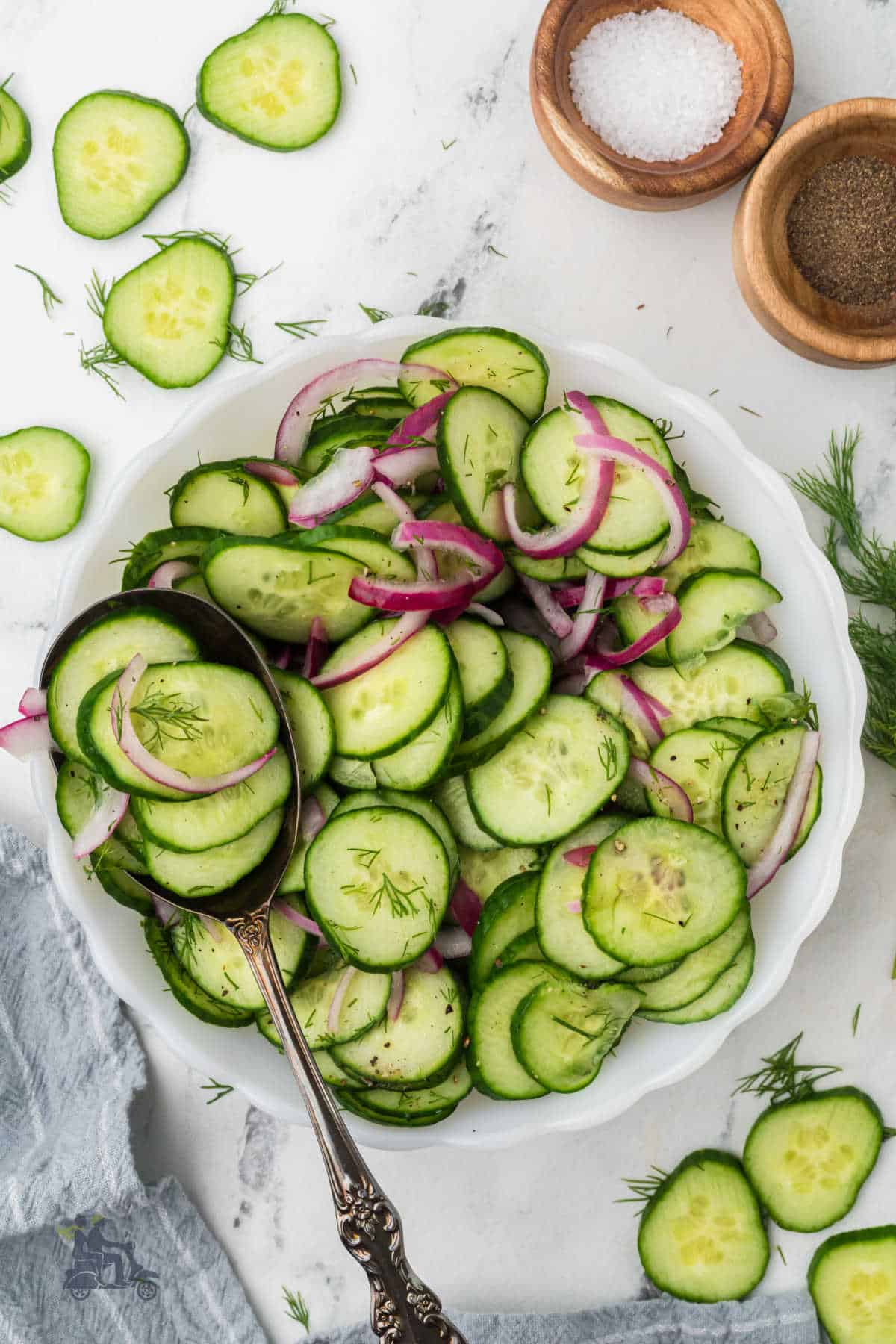 Fresh red onion and cucumber salad with dill and black pepper on a white tablecloth. 