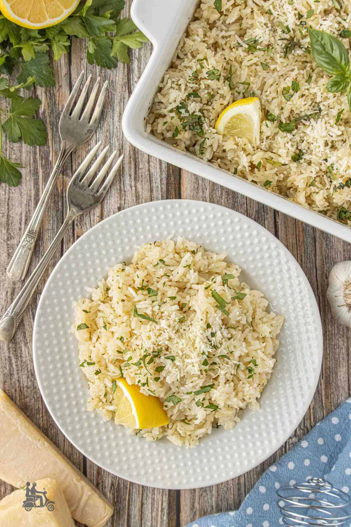 Overhead view of the oven baked rice topped with parmesan cheese, fresh parsley, and lemon.