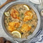 Creamy balsamic chicken and mushroom skillet in a pan with lemon wedges as garnish.