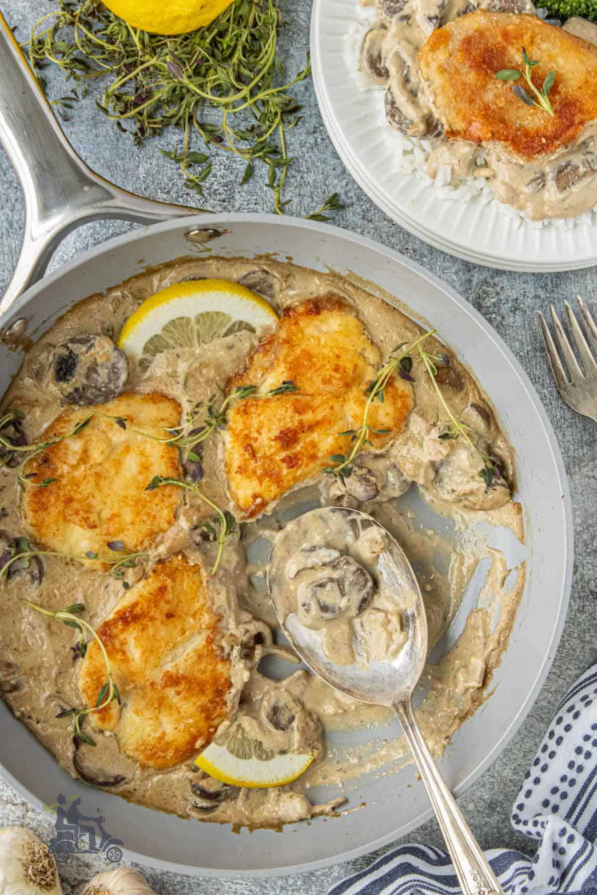 A spoon dips into the creamy balsamic mushroom made to cover the homemade one-skillet chicken cutlets.