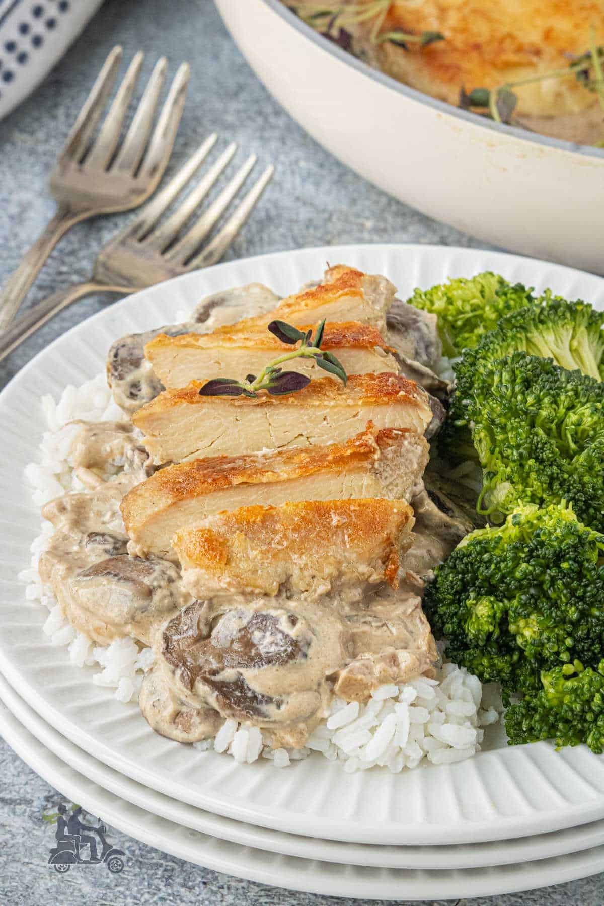 Homemade creamy chicken skillet recipe with the sliced meat on top of rice and broccoli on the side.