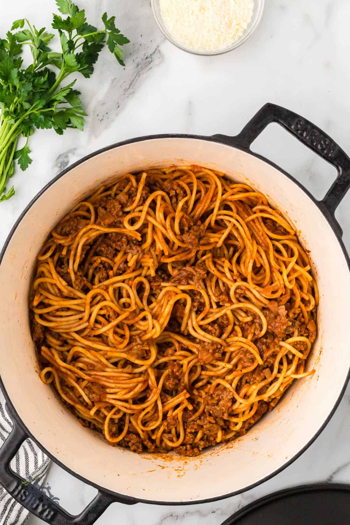 Dutch oven contains the finished spaghetti dinner recipe with ground beef.