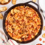 Cast iron skillet filled with cheesy pepperoni pizza dip served with crostini.