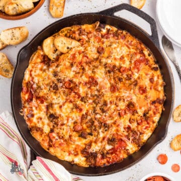 Cast iron skillet filled with cheesy pepperoni pizza dip served with crostini.