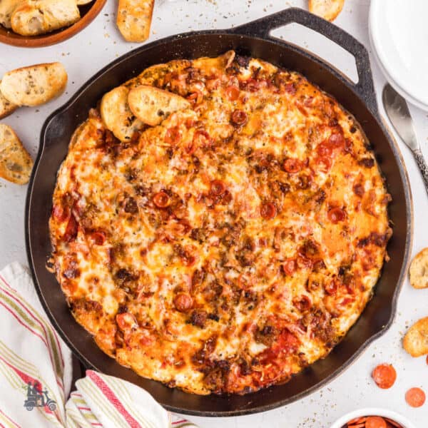 Cast iron skillet filled with cheesy pepperoni pizza dip served with crostini.